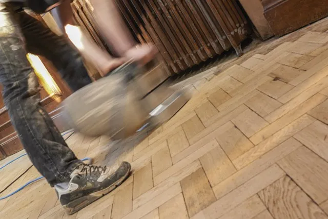 Man sanding reclaimed parquet floor
